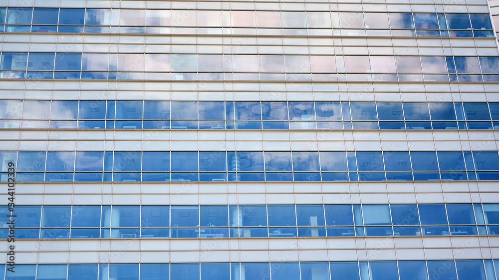 Modern office building windows with vertical lines and reflection. Building reflecting the sky with clouds and creating a surreal view. Modern office building windows with vertical lines and reflection. Building reflecting the sky with clouds and creating a surreal view.