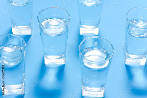 Glasses of water on a paper background. Drawing shadows. Classic Blue color. clean water concept