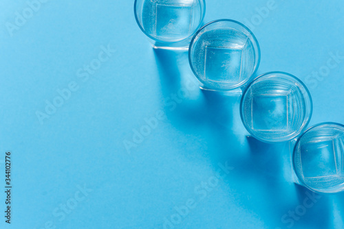 Line of glasses, a glass with water, on a light blue background. Difference concept. Equality concept.