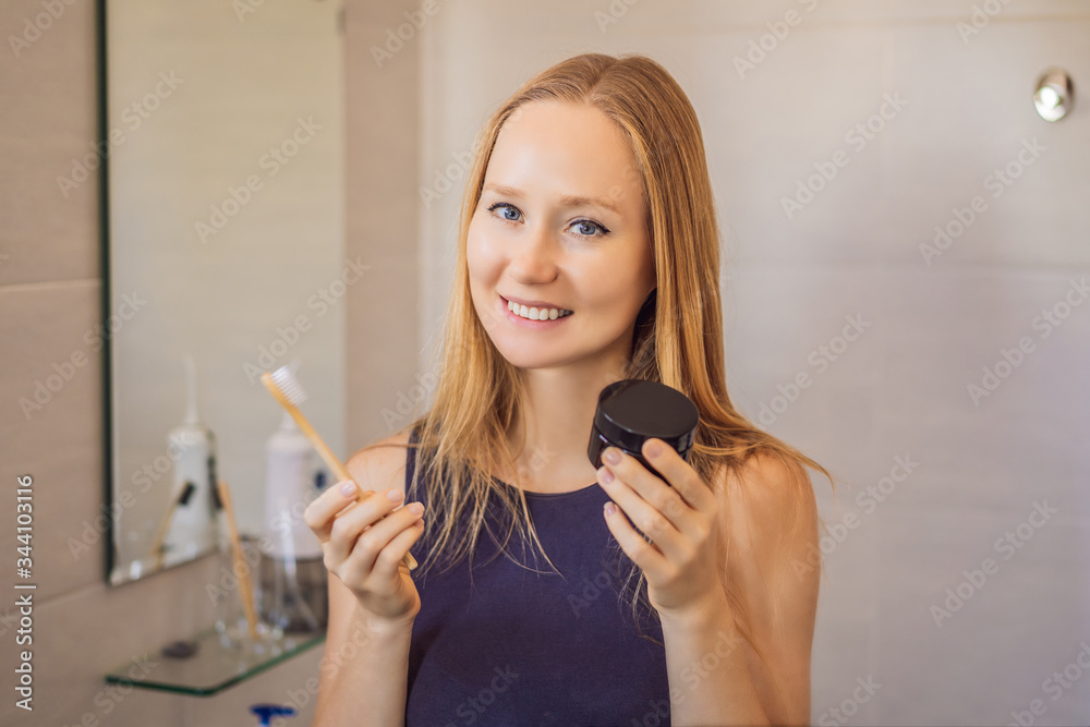 young woman brushing her teeth with a black tooth paste with active charcoal, and black tooth brush in her bathroom young woman brushing her teeth with a black tooth paste with active charcoal, and black tooth brush in her bathroom
