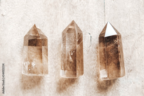 Three smoky natural quartz crystals on wooden background. Top view. Copy, empty space for text