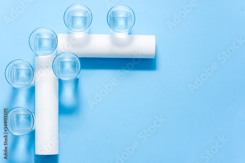 Glasses of dirty and clear water and filter cartridges to domestic water treatment systems at bright blue background. Concept of water treatment.