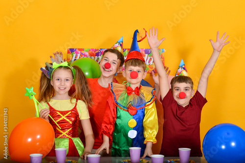 Four children celebrate a birthday with a clown at the table.