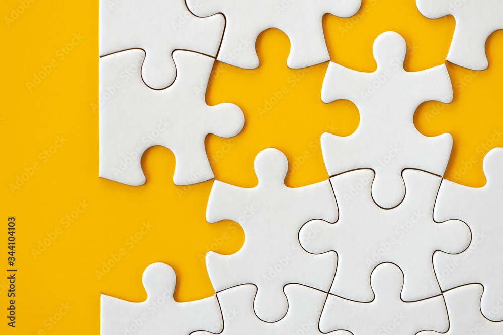 Puzzle pieces on orange background. White square puzzle pieces grid. Business background. Copy space for text, top view, close up. Puzzle pieces on orange background. White square puzzle pieces grid. Business background. Copy space for text, top view, close up.