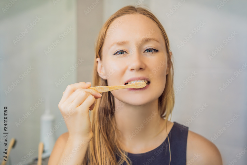 Young and caucasian woman brushing her teeth with a bamboo toothbrush Young and caucasian woman brushing her teeth with a bamboo toothbrush