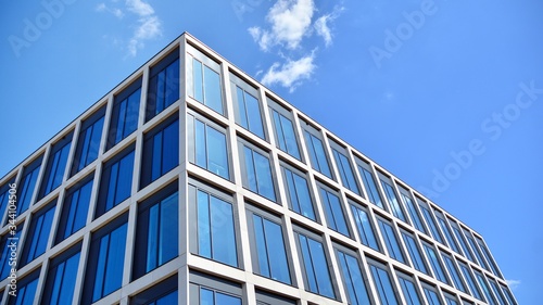 Modern office building windows with vertical lines and reflection. Building reflecting the sky with clouds and creating a surreal view.