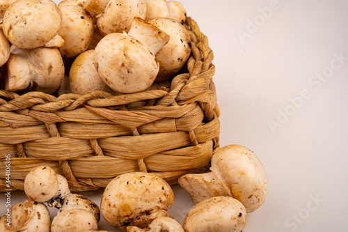 Young mushrooms in a wicker basket and young mushrooms scattered on a white background. Close up.