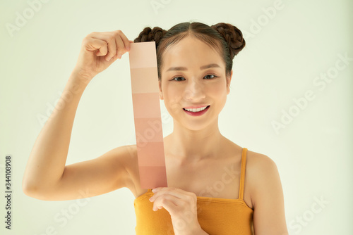 Young Asian woman showing color palette while standing isolated on light background.
