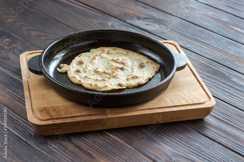 Pita bread in pan on dark wooden background. Natural food. Homemade bread. photo