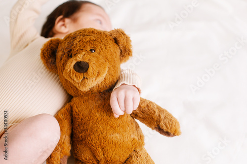 Baby with a bear toy on the bed
