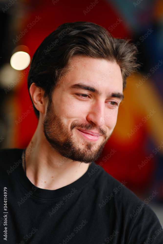 Close-up portrait of a young stylish man with a beard and dark hair in a black T-shirt Close-up portrait of a young stylish man with a beard and dark hair in a black T-shirt