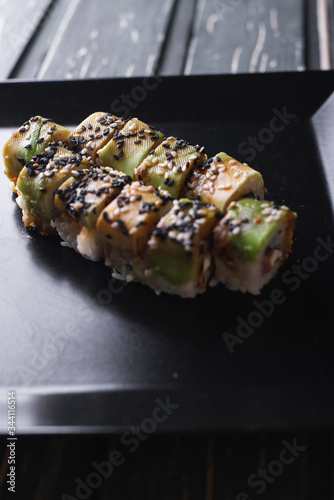 Salmon sushi on a square black plate on a dark wooden background