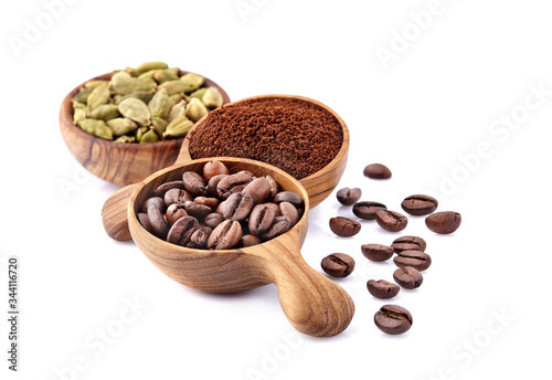 Coffee beans in a wooden spoon with cardamom on white background.