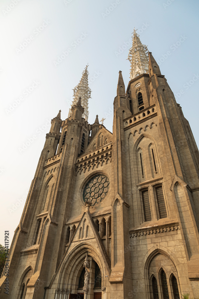 General and low-angle view of the portico of the main entrance to the Cathedral of Jakarta, on the Java Island, Indonesia, and its two towers, finished both in two white metal steeples on top.