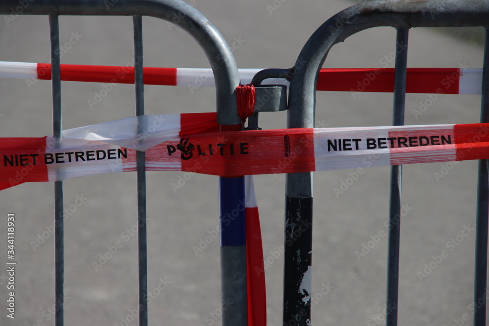 Red and white barrier tape of the Dutch police on a barrier at a crime scene Red and white barrier tape of the Dutch police on a barrier at a crime scene