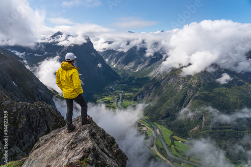A man traveller standing on rock looking to mountains, Romsdalseggen hiking trail, Norway, Scandinavia