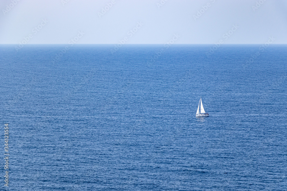 beautiful sailboat sailing in the distance in blue Mediterranean sea ocean, mallorca, spain