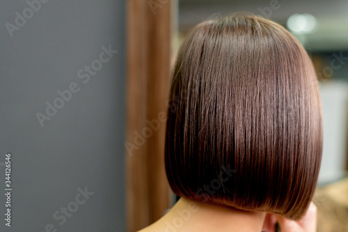Back view of short hairstyle of woman looking in the mirror in hair salon.