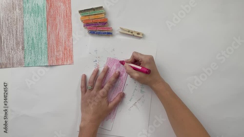 Woman coloring a piece of paper with anpink crayon photo