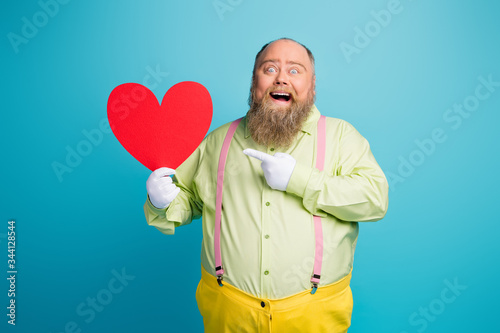 Portrait of his he nice funny funky cheerful cheery crazy man holding in hand demonstrating big large heart card isolated over bright vivid shine vibrant blue color background