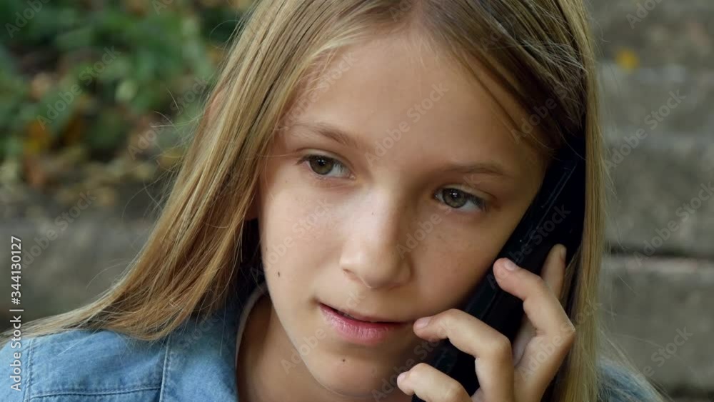 Child Talking on Smartphone, Kid Using Smart Phone, Teenager Girl Playing Outdoor in Park Child Talking on Smartphone, Kid Using Smart Phone, Teenager Girl Playing Outdoor in Park