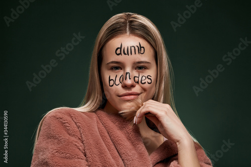 Modern Art activity about civilized society without social barriers due to racial and sexual bias. A young blonde lady in a beige bathrobe is labeled with a cliche phrase on her face 