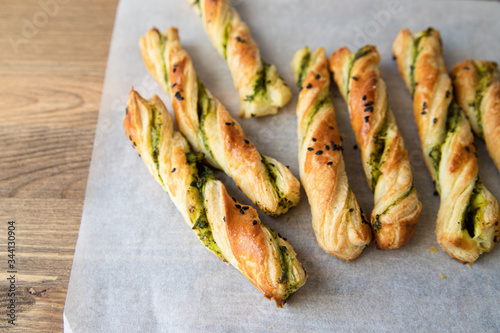 salty sticks of puff pastry sprinkled with cumin and greenery on a wooden background