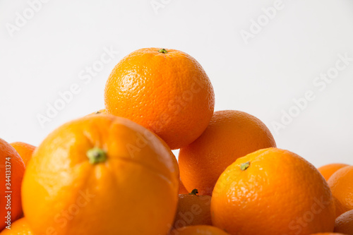 Top of whole orange fruits heap isolated on white background. Side view  closeup. Natural vitamin or organic food concept