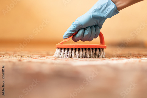 A female hand in a glove that cleans the carpet. House cleaning process. Carpet brushing