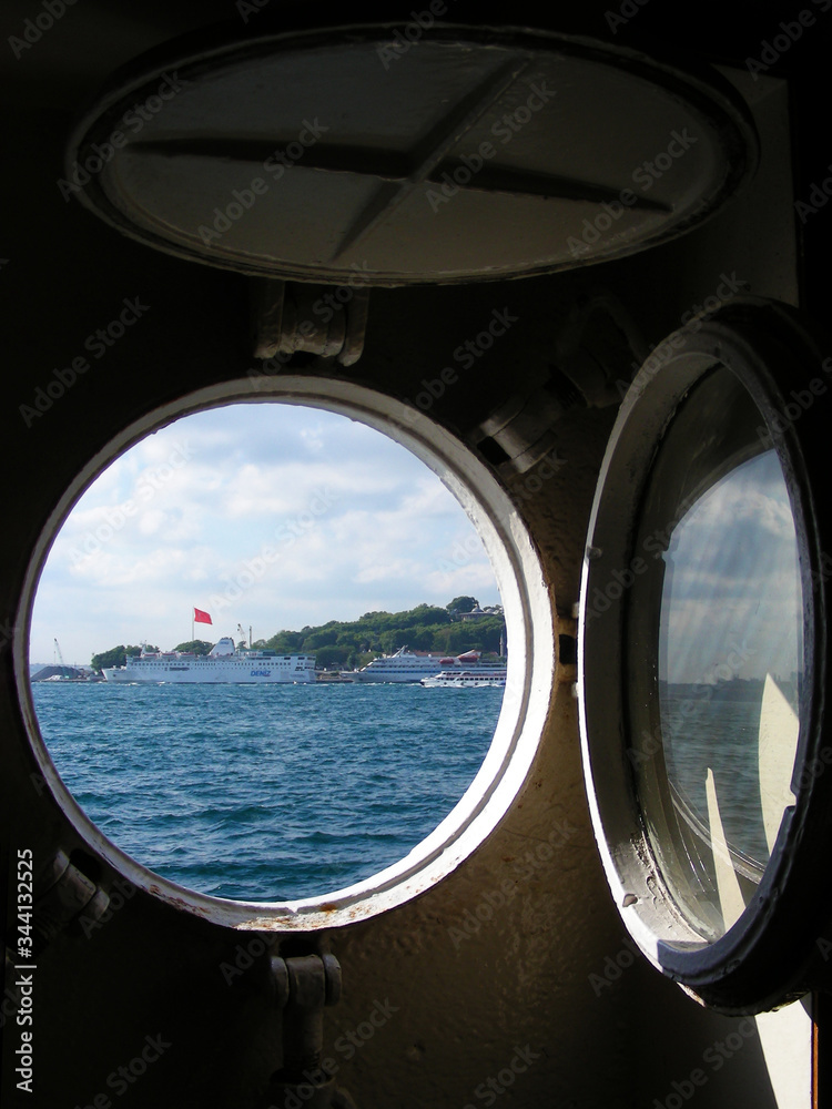 View from the ship’s cabin through a round porthole, on a green sea island. Sea transport concept. Transportation of people by sea