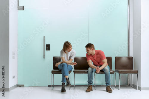 Pretty girl shows her boyfriend good tests on a smartphone and waiting for a doctor's appointment in a hospital.