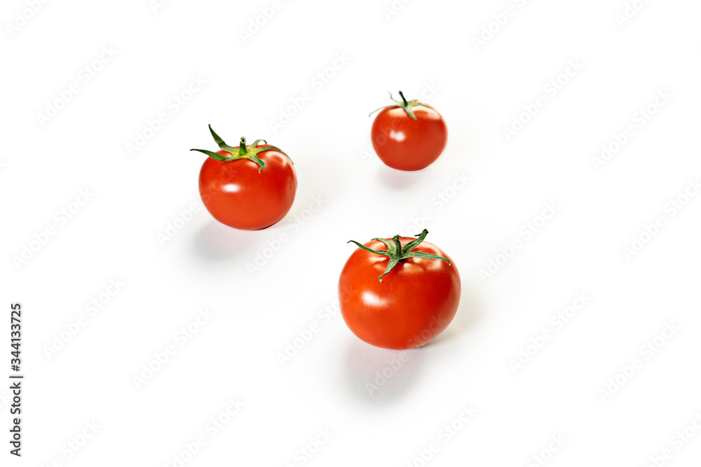 Three red tomatoes stand on a white background. Tomatoes form a triangle. The background is in defocus. Bright color, isolated objects. Three red tomatoes stand on a white background. Tomatoes form a triangle. The background is in defocus. Bright color, isolated objects.