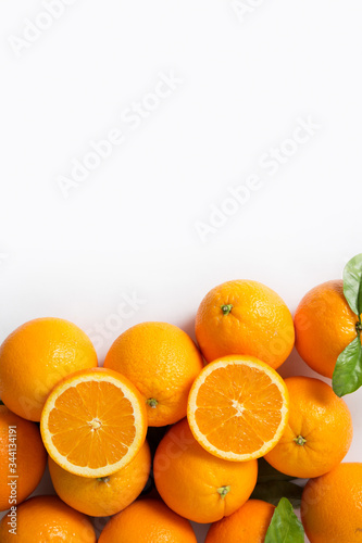 Whole and cut orange fruits with green leaves isolated on white background. Vertical shot, top view, copy space. Natural vitamin or organic food concept