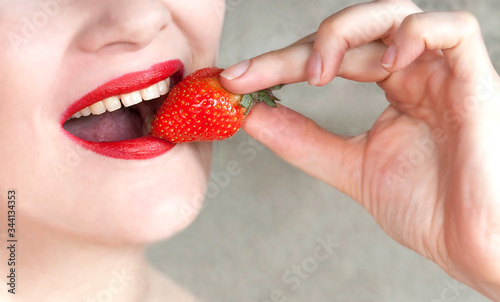 young woman with red lipstick eating strawberries