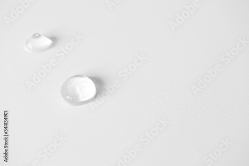 Close-up drops transparent cosmetic aloe vera gel lotion on white background with copy space and selective focus. Body care and skin care © Olha Kozachenko