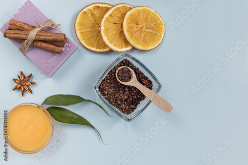 On a blue background are care products: lavender soap and mango cream for face and body after, coffee scrub. For aromatherapy: cinnamon sticks, anise star, sliced orange circles. Spa concept.