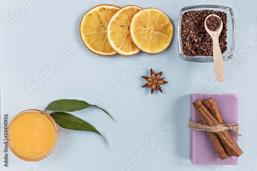 On a blue background are care products: lavender soap and mango cream for face and body after, coffee scrub. For aromatherapy: cinnamon sticks, anise star, sliced orange circles. Spa concept.