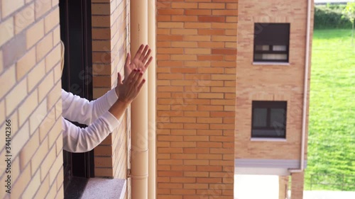 Woman claps from the window of her house in the quarantine of the state of alarm by the coronavirus