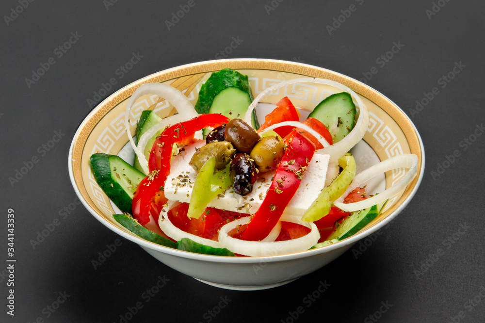 Ceramic bowl with fresh cucumber, tomato, onion, paprika, feta and marinated olives salad on grey background Ceramic bowl with fresh cucumber, tomato, onion, paprika, feta and marinated olives salad on grey background