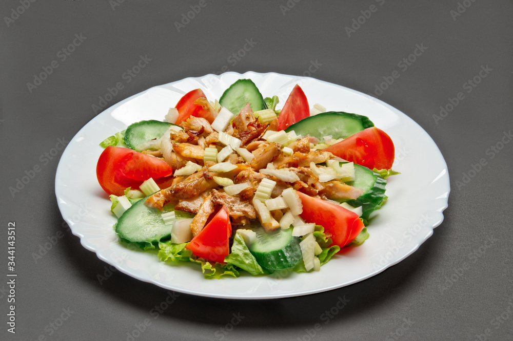 White ceramic plate with fresh tomatoes, cucumber, celery, lettuce and meat salad on grey background White ceramic plate with fresh tomatoes, cucumber, celery, lettuce and meat salad on grey background
