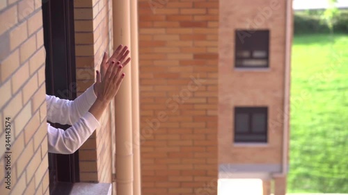 Woman claps from the window of her house in the quarantine of the state of alarm by the coronavirus