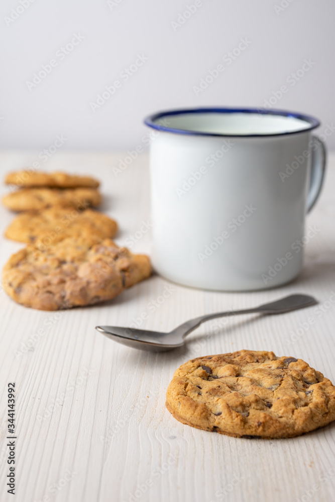 Top view of chocolate chip cookie with white cup and spoon, with selective focus, on white background, vertical Top view of chocolate chip cookie with white cup and spoon, with selective focus, on white background, vertical
