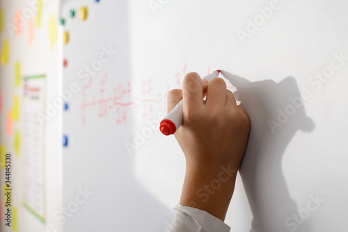 Hand of a young learner on the board writing some math eguation. Concept of math lesson in secondary school