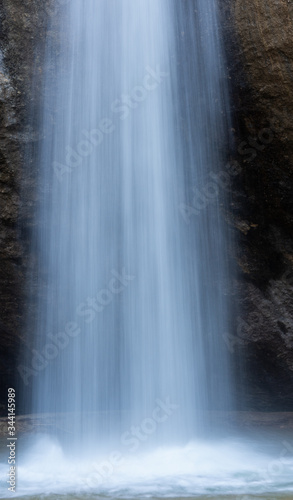 Blurred water of the waterfall close up. Beautiful abstract drawing of water on a long exposure. The vertical flow of water up close. Winter waterfall Visor Crimea.