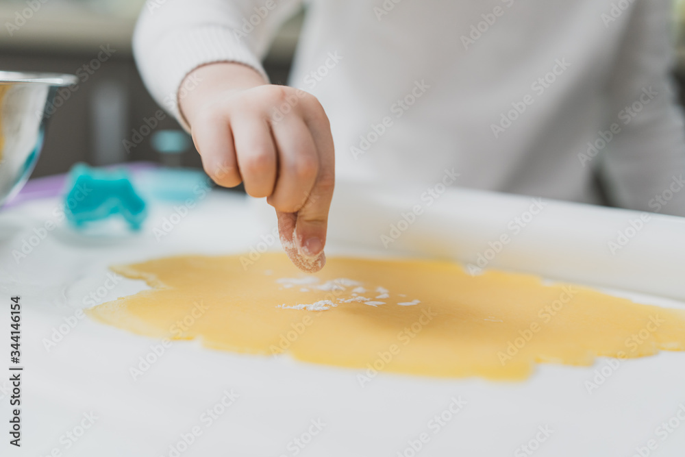Perfect shortcrust pastry on the surface, a child's hand sprinkles it with flour, making cookies Perfect shortcrust pastry on the surface, a child's hand sprinkles it with flour, making cookies