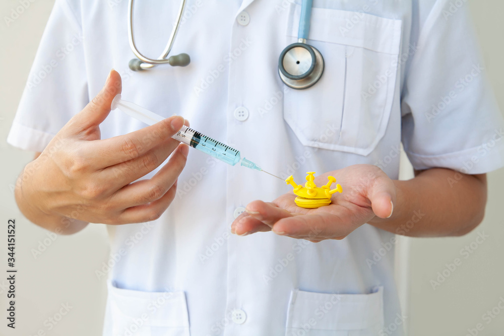 Coronavirus vaccine. Closeup of doctor injecting vaccine into coronavirus model. Concept of medical research for coronavirus vaccine. Prevention and treatment of coronavirus infection. Selective focus