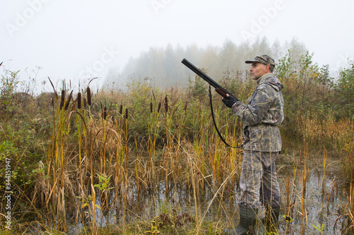 the hunter stood at the edge of the swamp with his shotgun ready