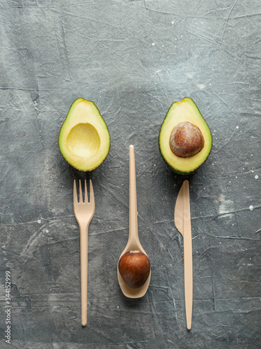 Avocado Seeds Biodegradable Single-Use Cutlery. Bioplastic - Great alternative to plastic disposable cutlery. Top view, flat lay. Copy space for text or design. Gray background. Vertical photo