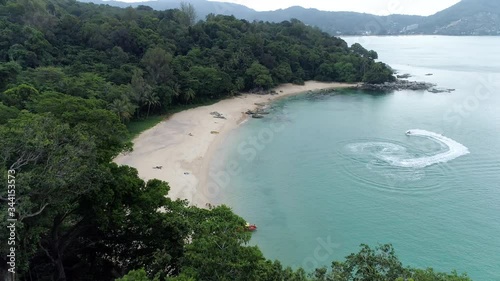 The Wonderful View Of The Lush Green Island In PhuketThailand Surrounded With Deep Blue Ocean On A Sunny Day - Jet Ski Moving Near Seashore - Aerial Shot photo