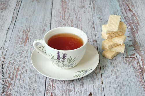 Top view of a mug with red tea and wafer biscuits on wooden table
